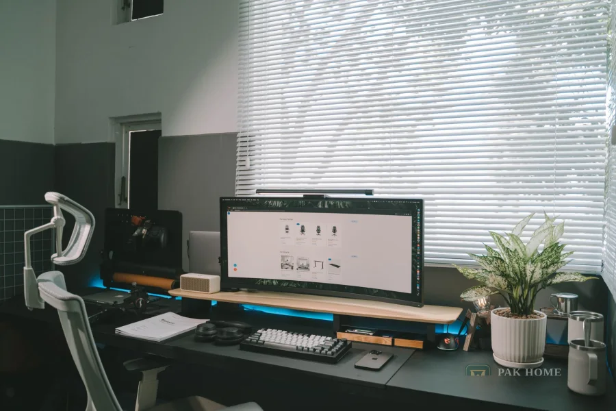 Office desk with a monitor beside a window fitted with horizontal blinds