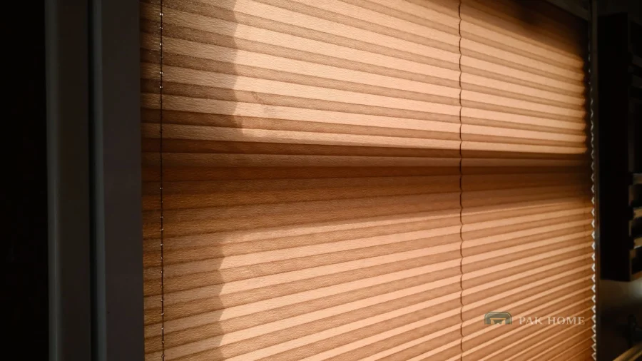 Warm afternoon sun striking a wooden venetian blind and casting slat shadows indoors