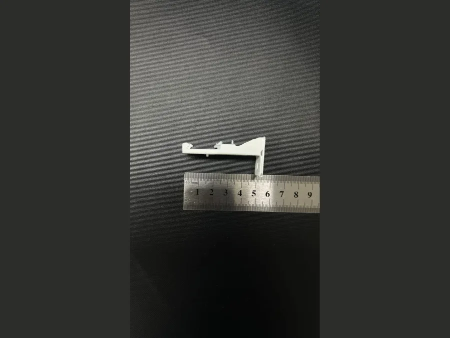 White curtain track wall bracket beside a steel measuring ruler