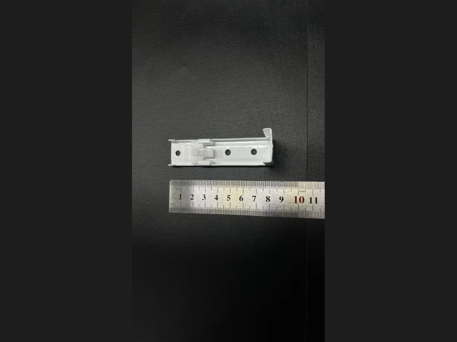 Compact white curtain track ceiling bracket with a ruler for scale