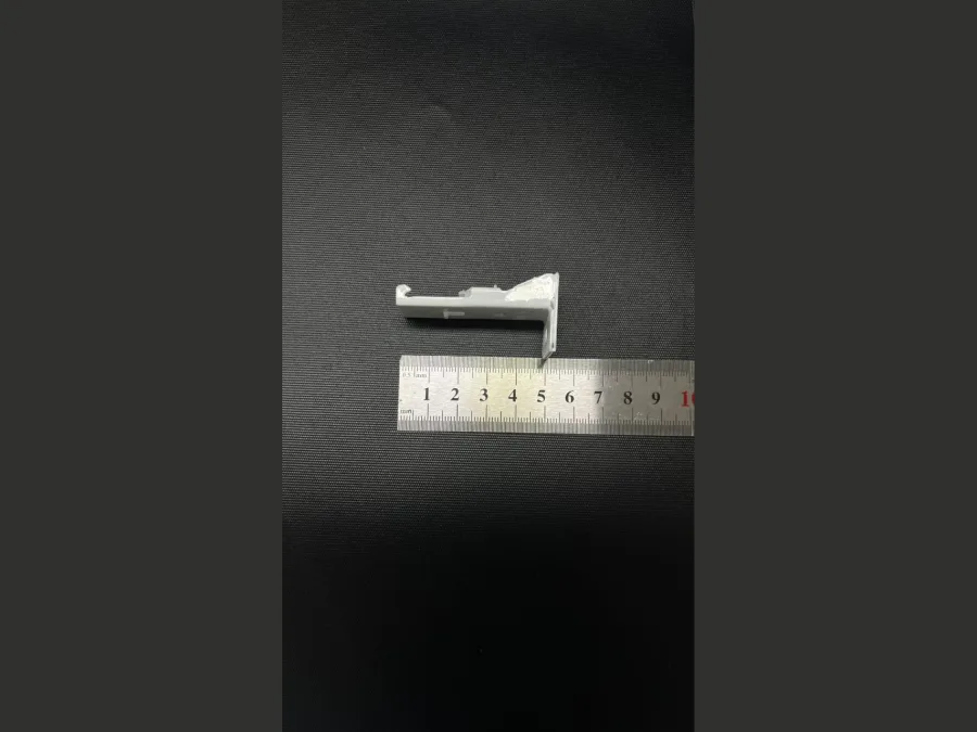 Low-profile white curtain track bracket on a measuring ruler