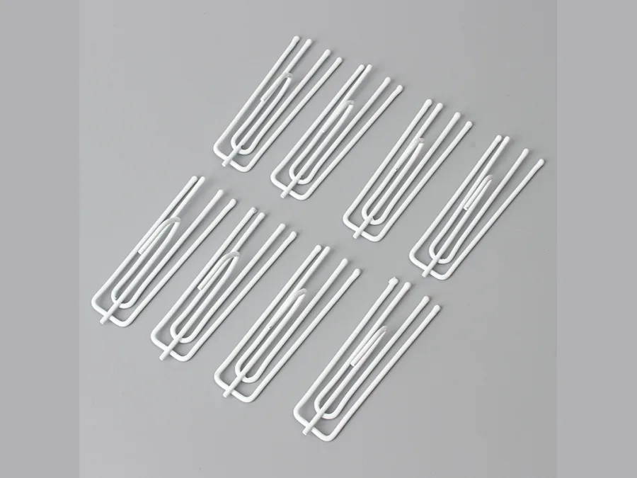 Set of metal pinch pleat curtain hooks laid out side by side
