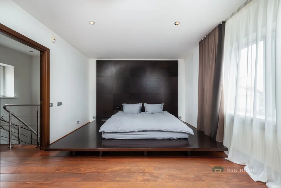 Full-height curtains on a ceiling track in a bedroom beside a staircase handrail