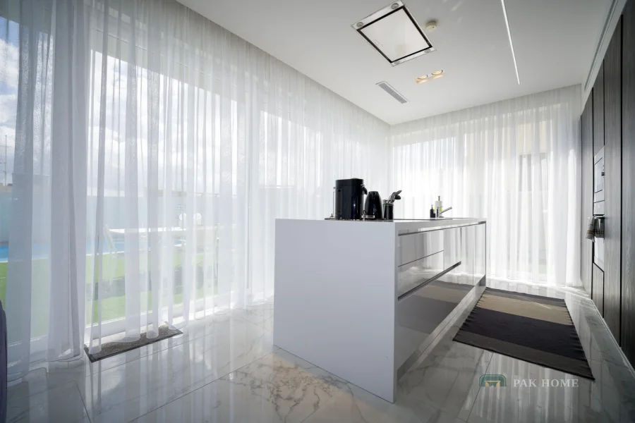 Sheer curtains on a ceiling track running the full width of a villa kitchen window